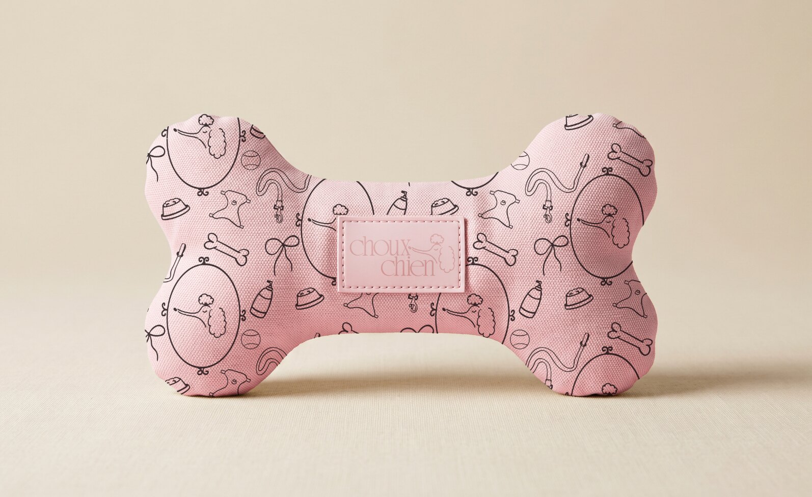 Pink bone-shaped Choux Chien dog toy with illustrated pet pattern and branded label