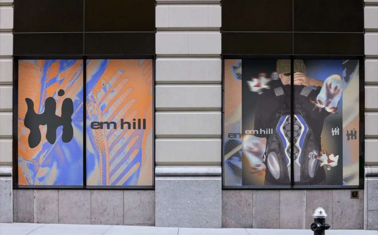 Em Hill orange, blue, and black campaign graphics installed across storefront windows